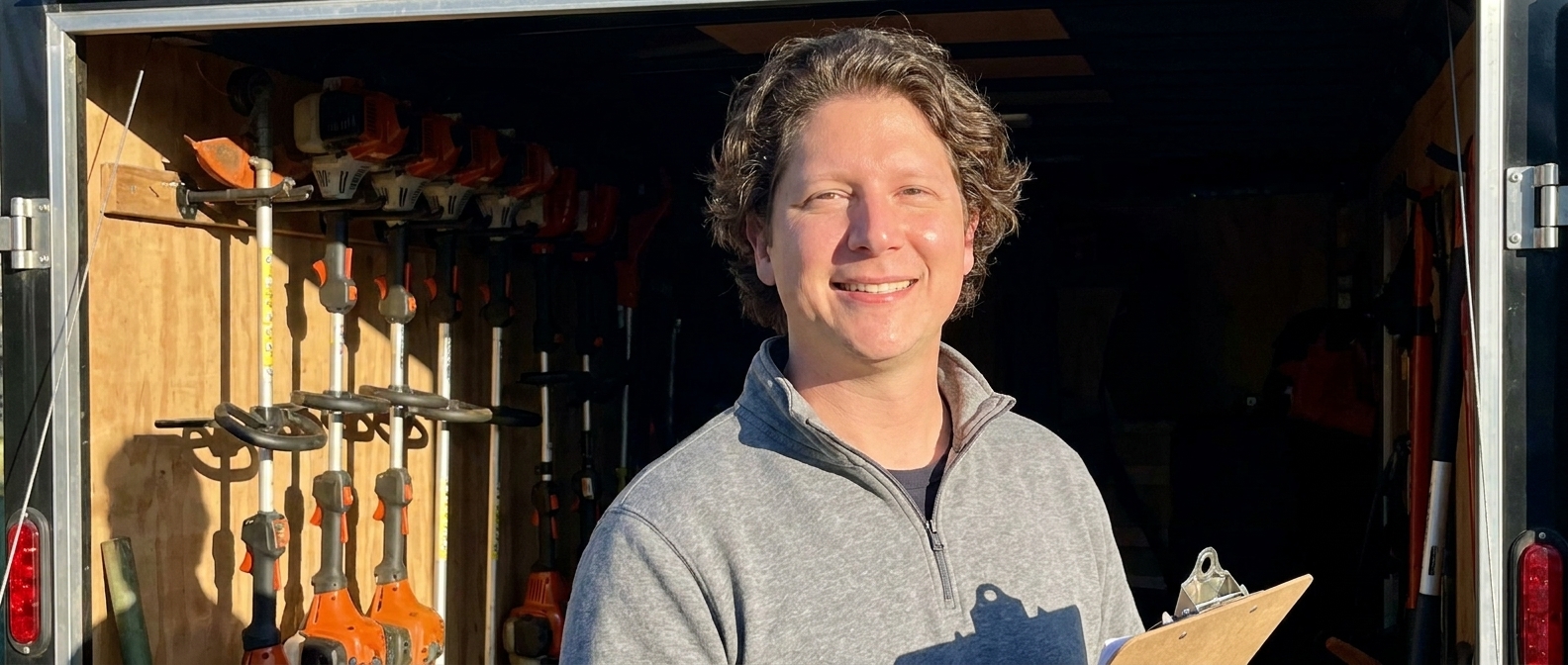 Vincent Jordan at an open equipment trailer with trimmers racked behind him